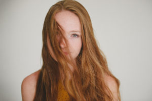 red head, blue eyed freckled girl in white studio