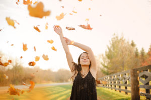 Fall leaves blowing over senior girl